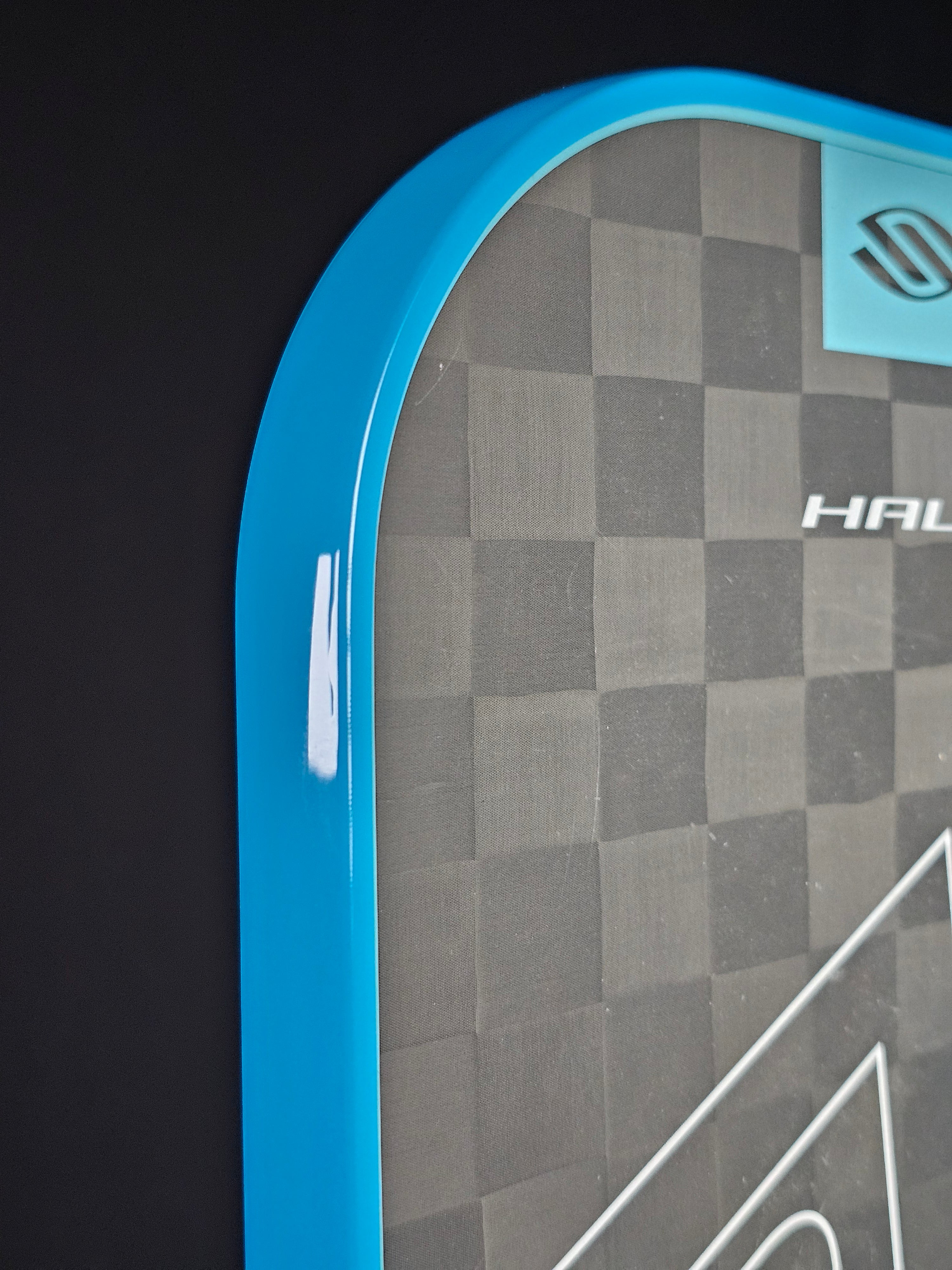 Close-up of a Selkirk pickleball paddle with bright blue edge tape