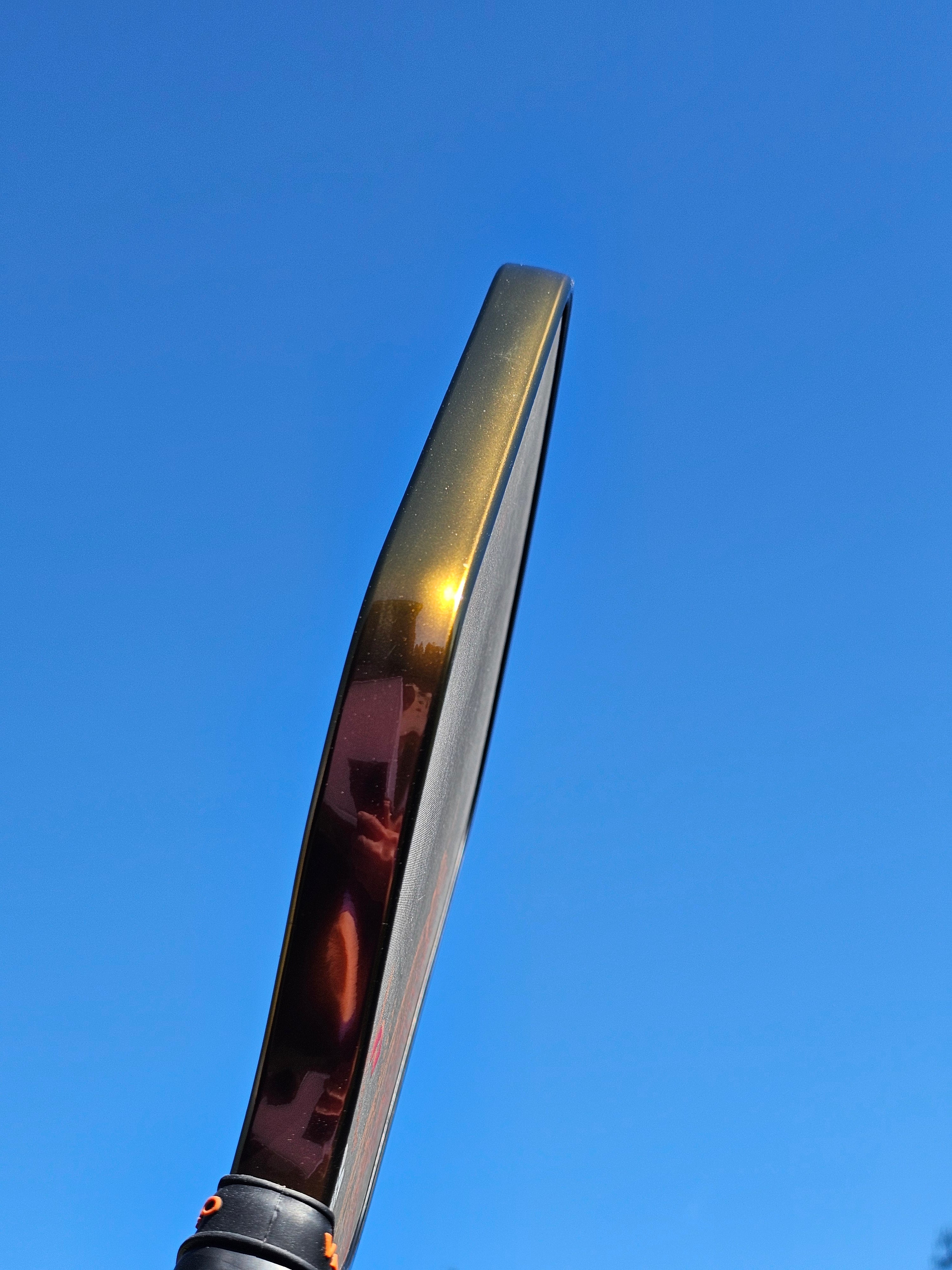 Close-up of a pickleball paddle with Bronze color shift edge tape shifted to a rich gold color