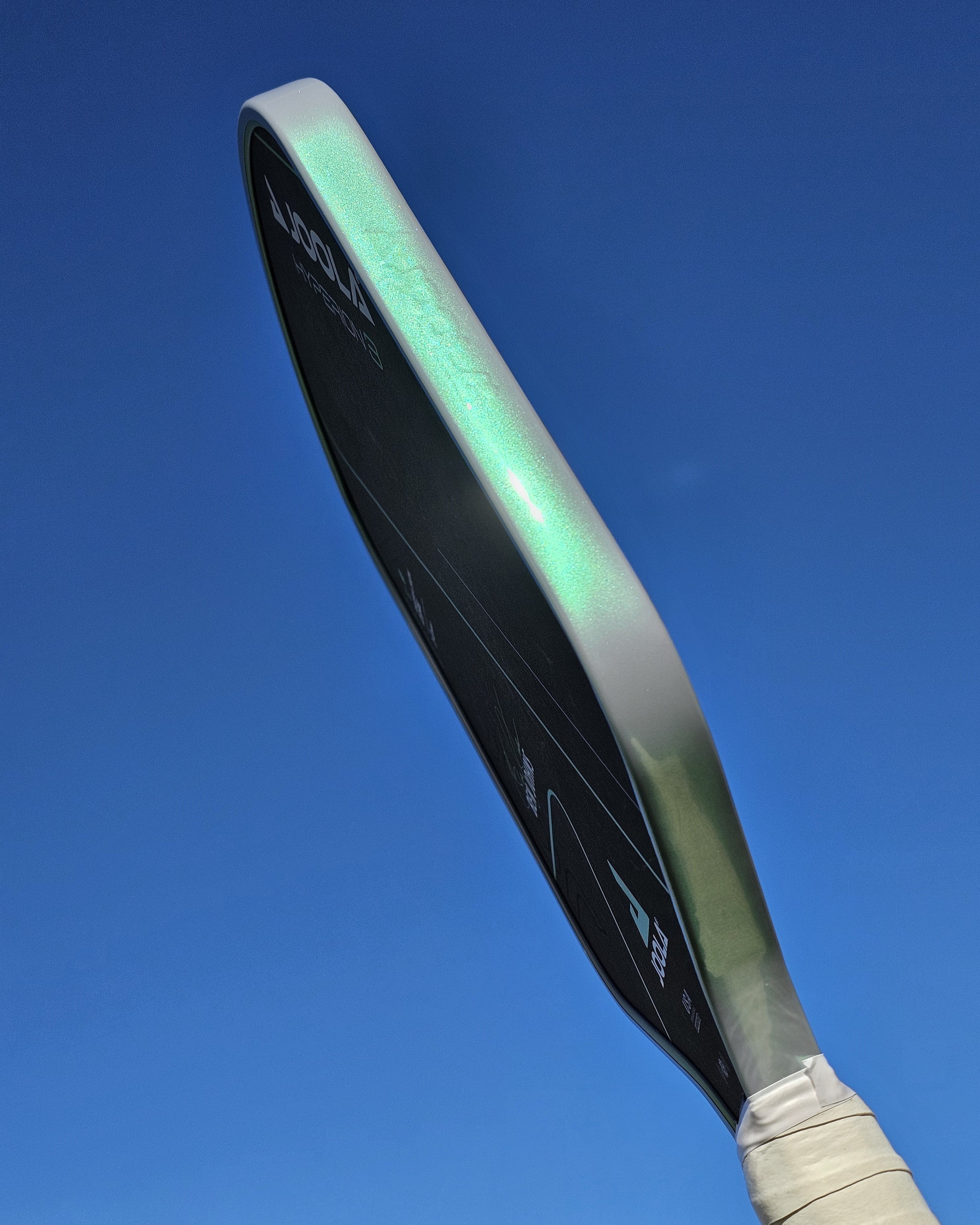 Joola Hyperion pickleball paddle with grey/green edge tape against a sky backround