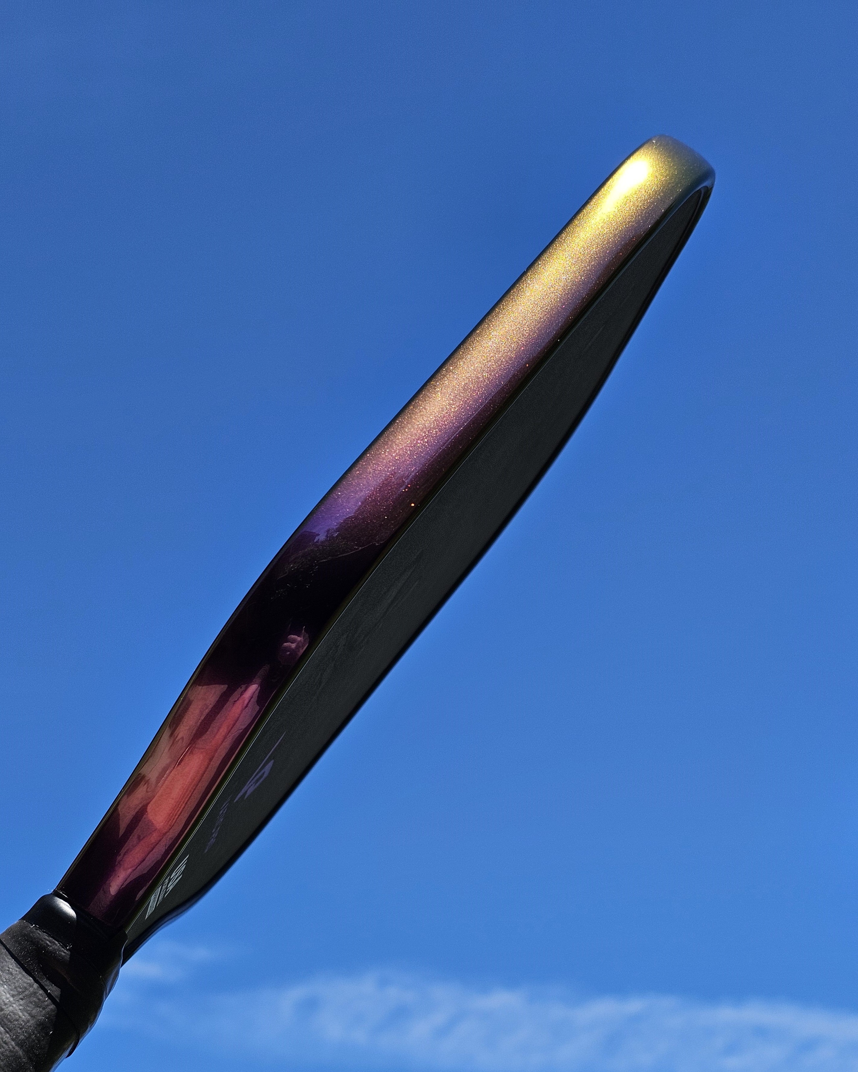 Close-up of a pickleball paddle with indigo sunset color shift edge tape