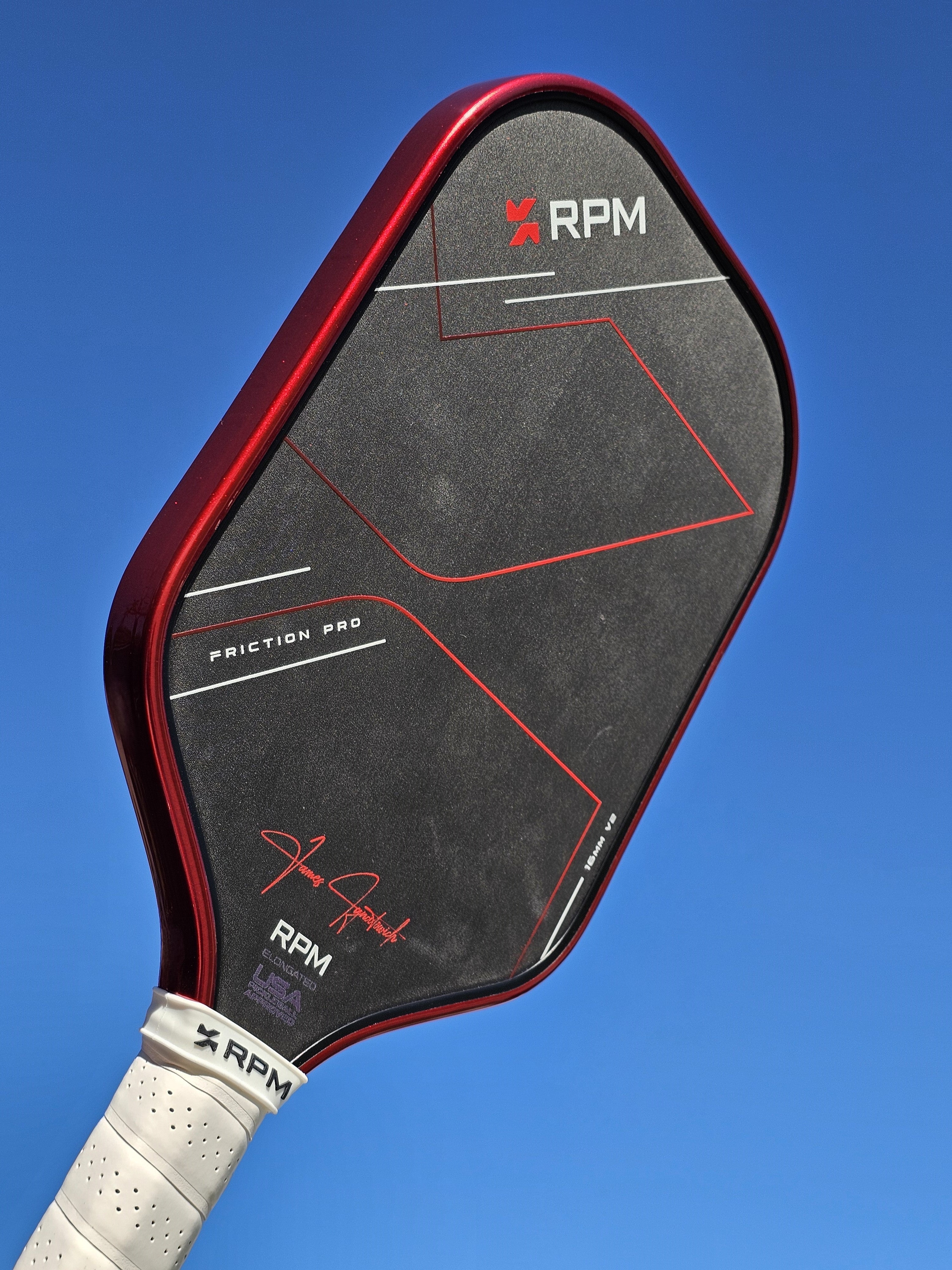 RPM Pickleball paddle with #48 Red Candy Metallic edge tape shown against a sky background