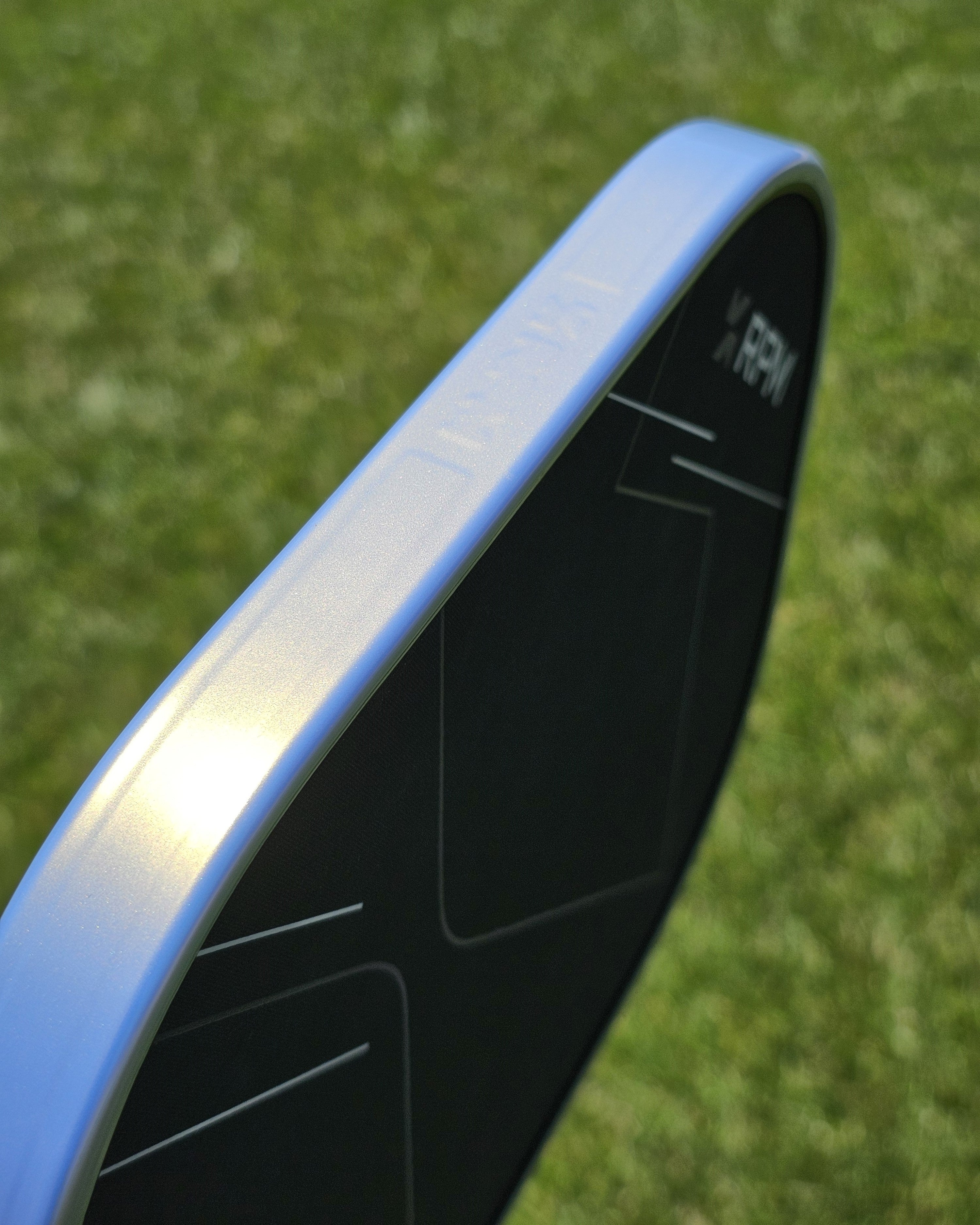 Close-up of a pickleball paddle showing a platinum and gold protective edge guard tape