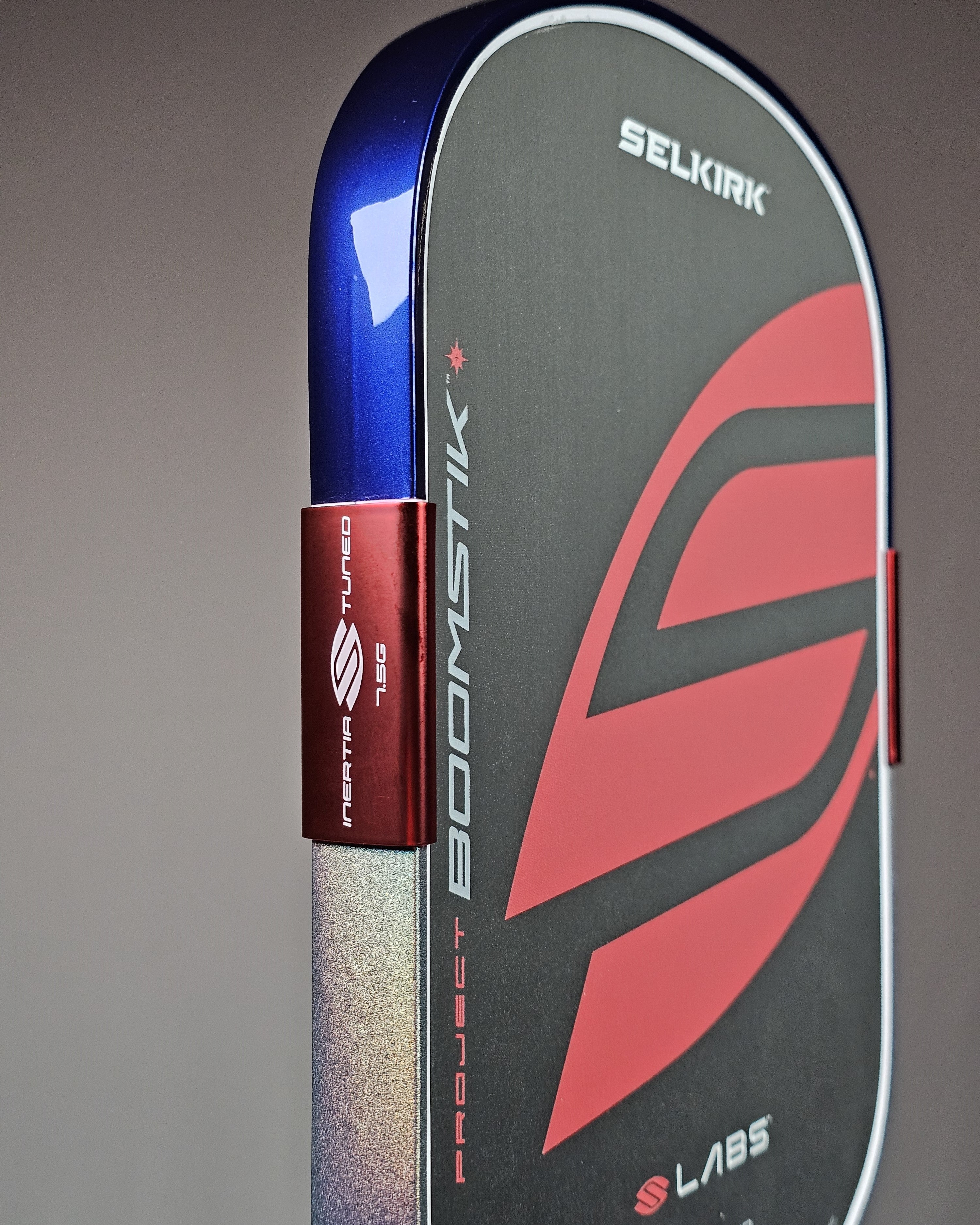 Close-up of a SelkirkBoomstik pickleball paddle with 2-tone Deep Blue Metallic and Silver Prism Captain America edge tape