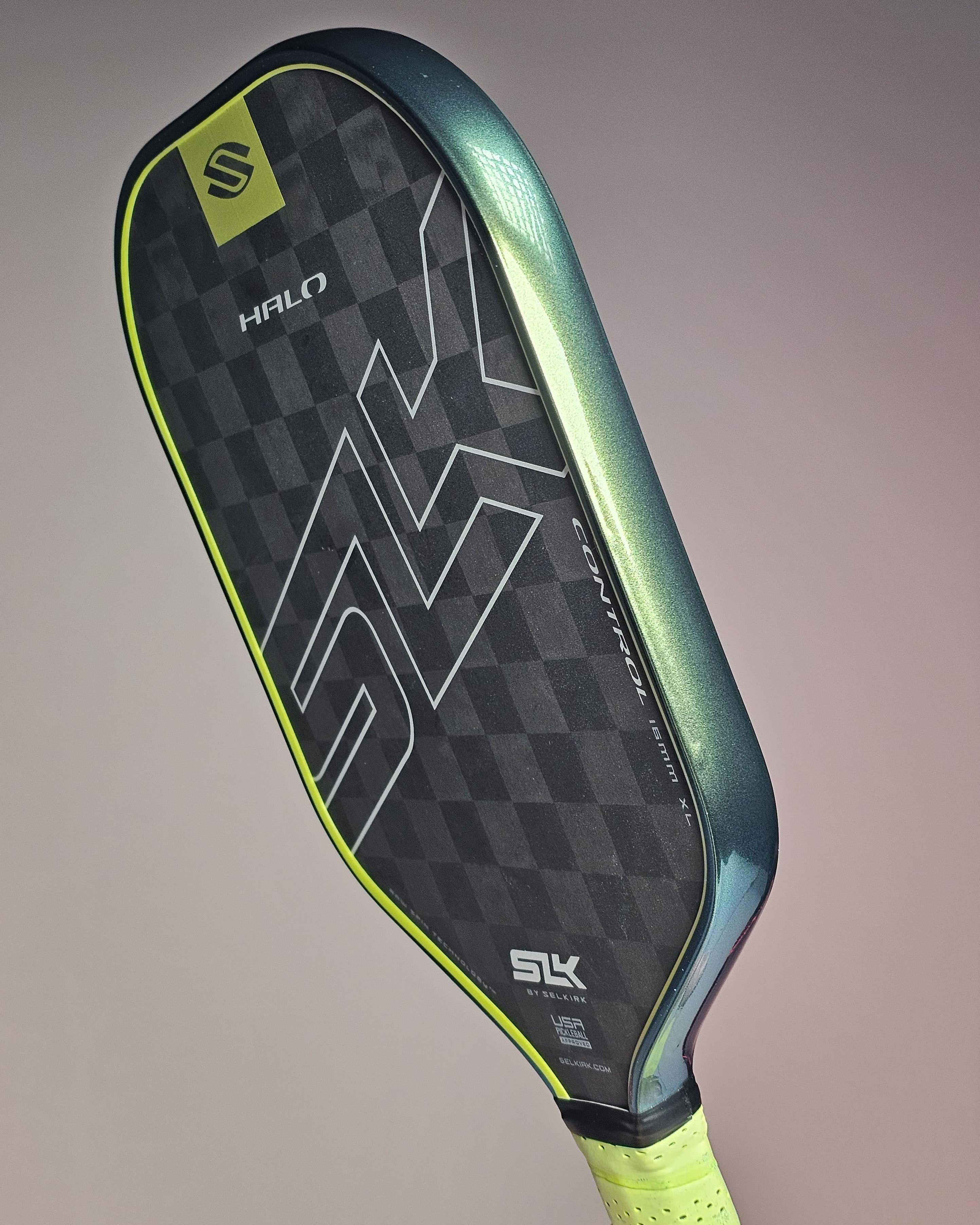 Pickleball paddle with green edge guard tape on a gray background