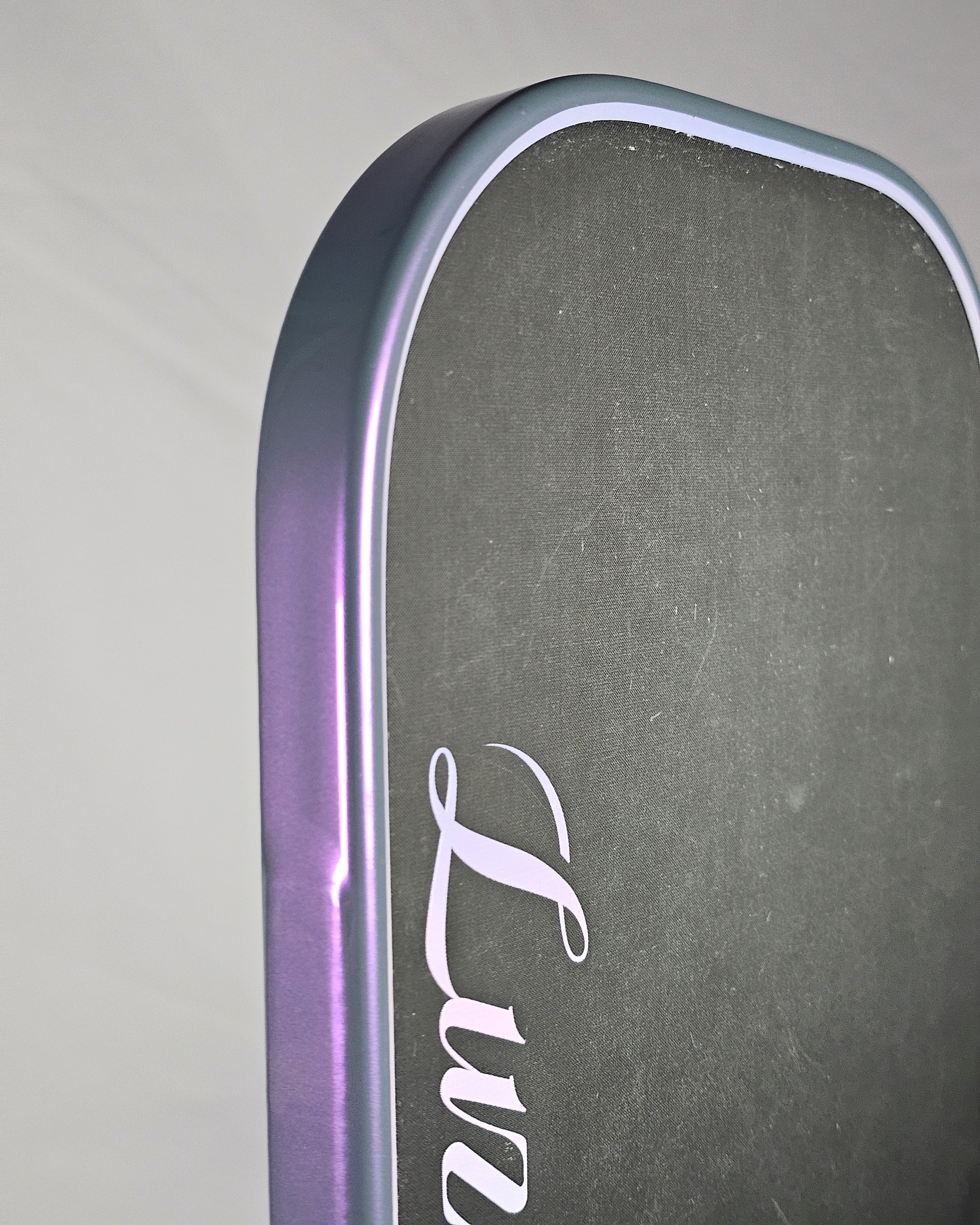 Close-up of a Luzz Tornazo pickleball paddle with grey/purple edge tape